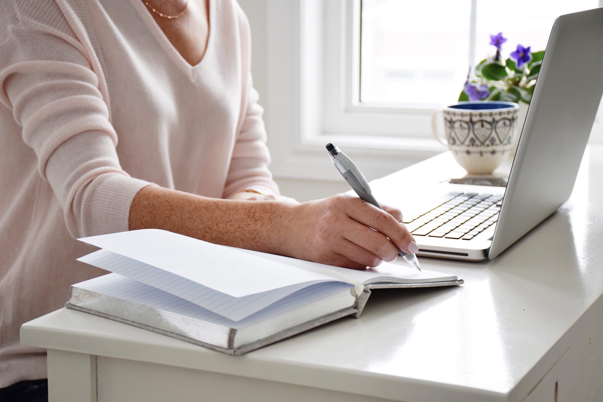 A female entrepreneur outsourcing staff for her multiple businesses, taking notes from a candidate via online interview