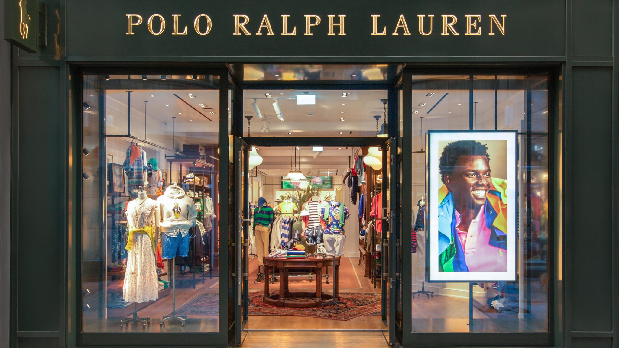 The storefront of a Polo Ralph Lauren store with mannequins displaying clothing inside and the Polo Ralph Lauren logo above the entrance