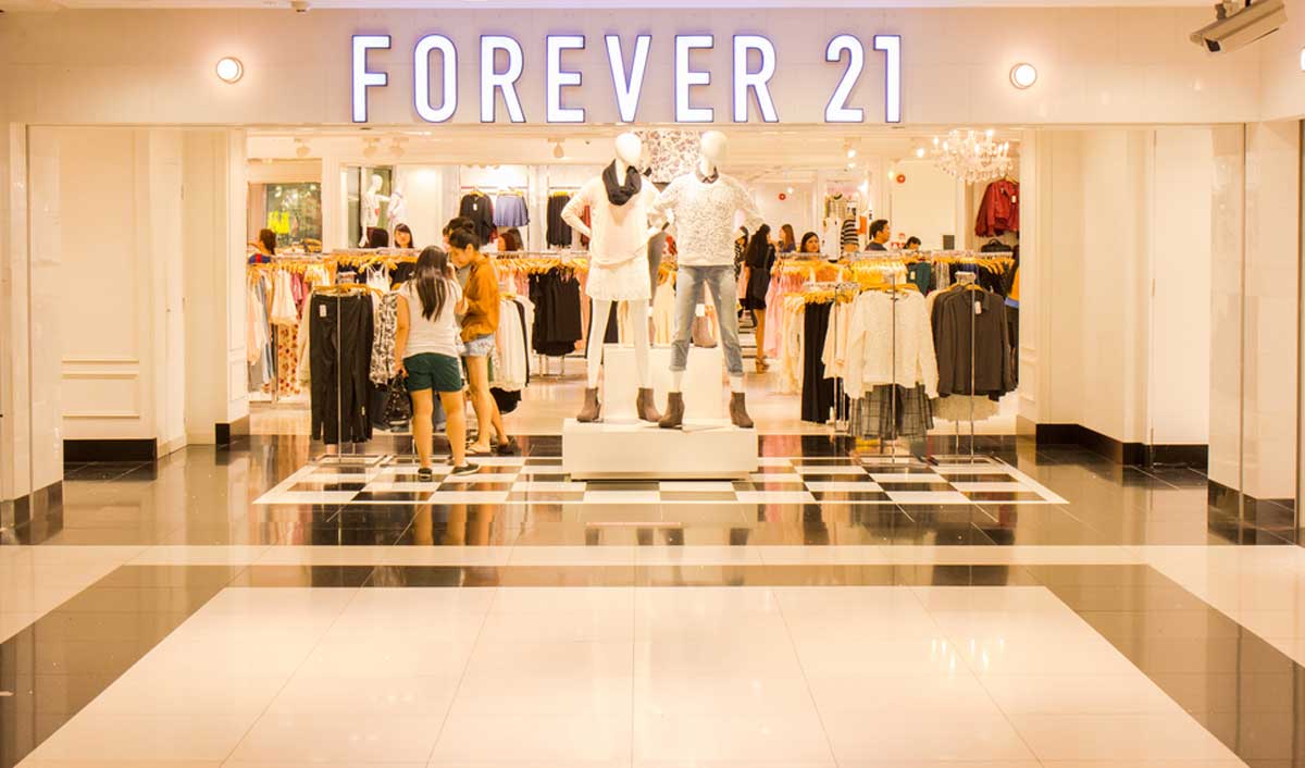 The entrance of a Forever 21 store with mannequins displaying fashionable clothing and the Forever 21 logo prominently displayed above the doorway