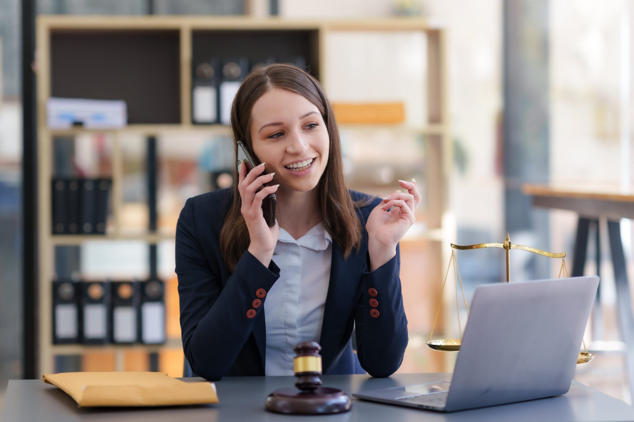 A lawyer in her office, speaking with a client on the phone while working on her laptop, demonstrating the importance of Local SEO for law firms