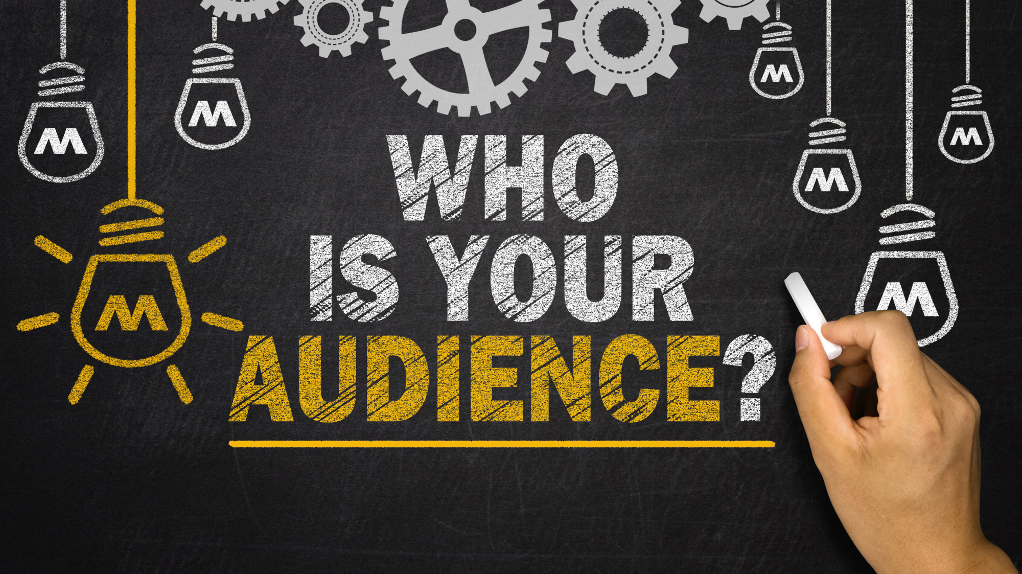 Hand writing on chalkboard with 'Who is your audience?' highlighting the importance of understanding target audiences for content creation