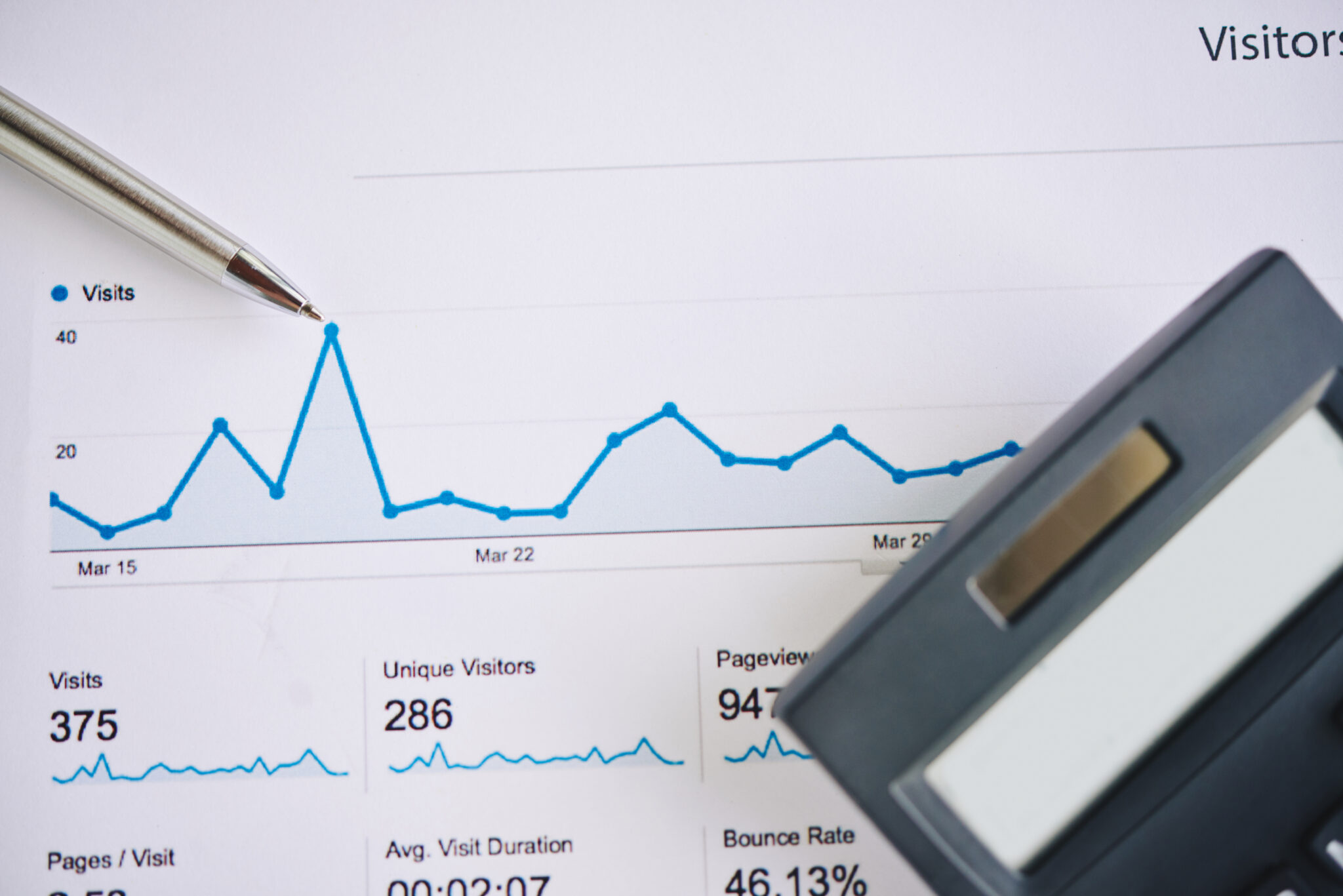 SEO dashboard showing website statistics and visitor data, alongside a pen and tablet for analytics evaluation