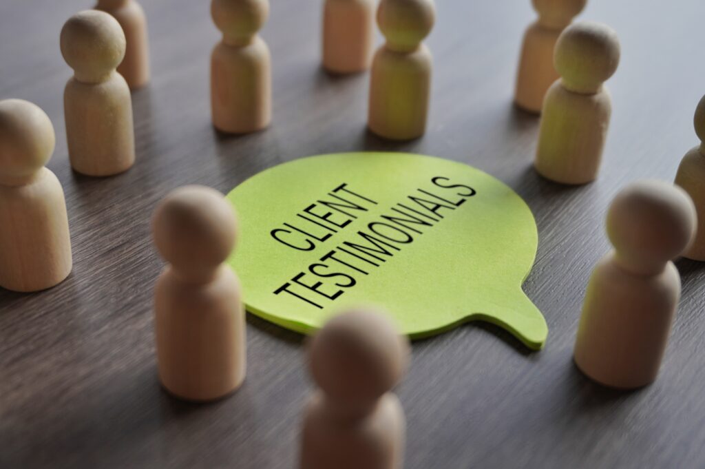Wooden figures around a green speech bubble labeled 'Client Testimonials,' representing the power of testimonials in building trust and credibility