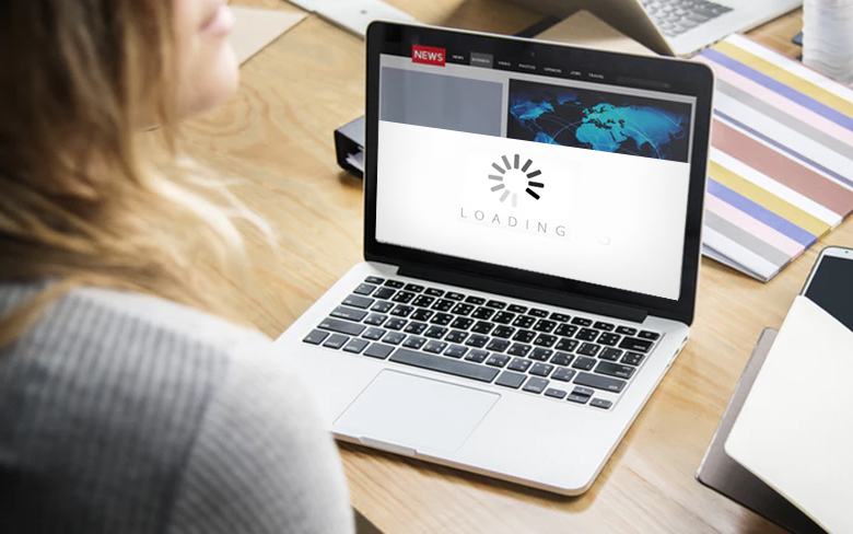 Person sitting at a desk, waiting for a news website to load on a laptop, illustrating update your website. This image highlights the need for faster loading times and better website optimization to improve user experience