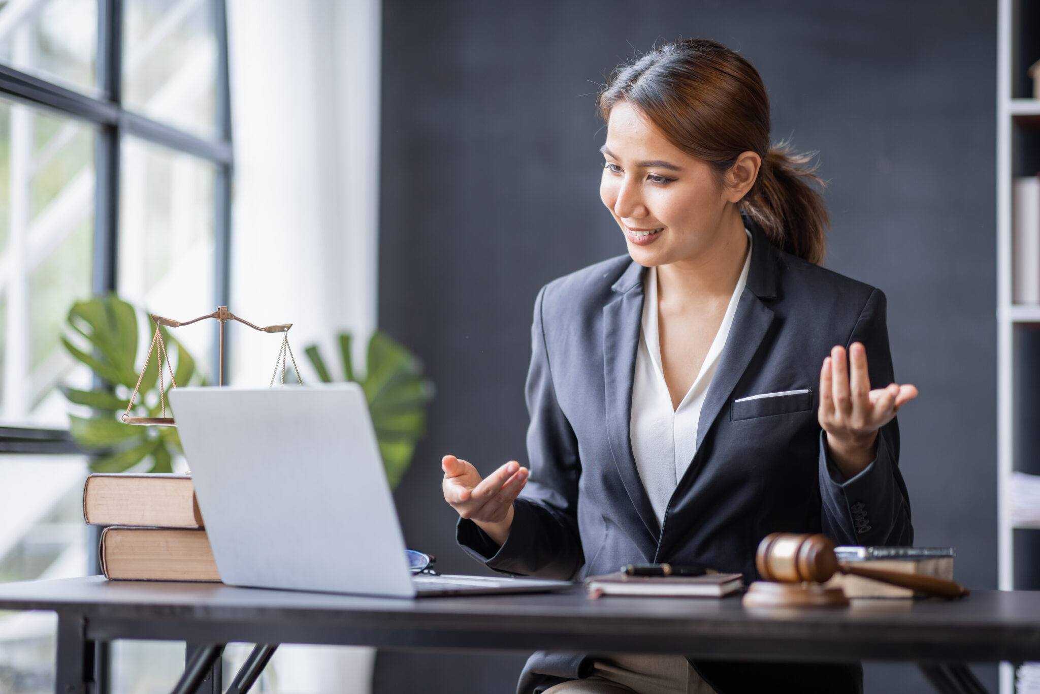 A professional woman in a business suit works at a desk with a laptop, representing content marketing for law firms