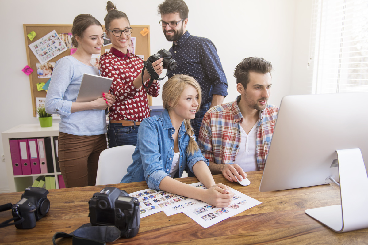 A group of individuals collaborates around a table with a laptop, representing a Houston social media agency meeting