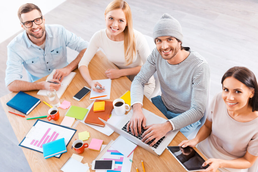 A group of professionals collaborating at a table with laptops in a Houston social media agency setting