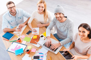 A group of professionals collaborating at a table with laptops in a Houston social media agency setting