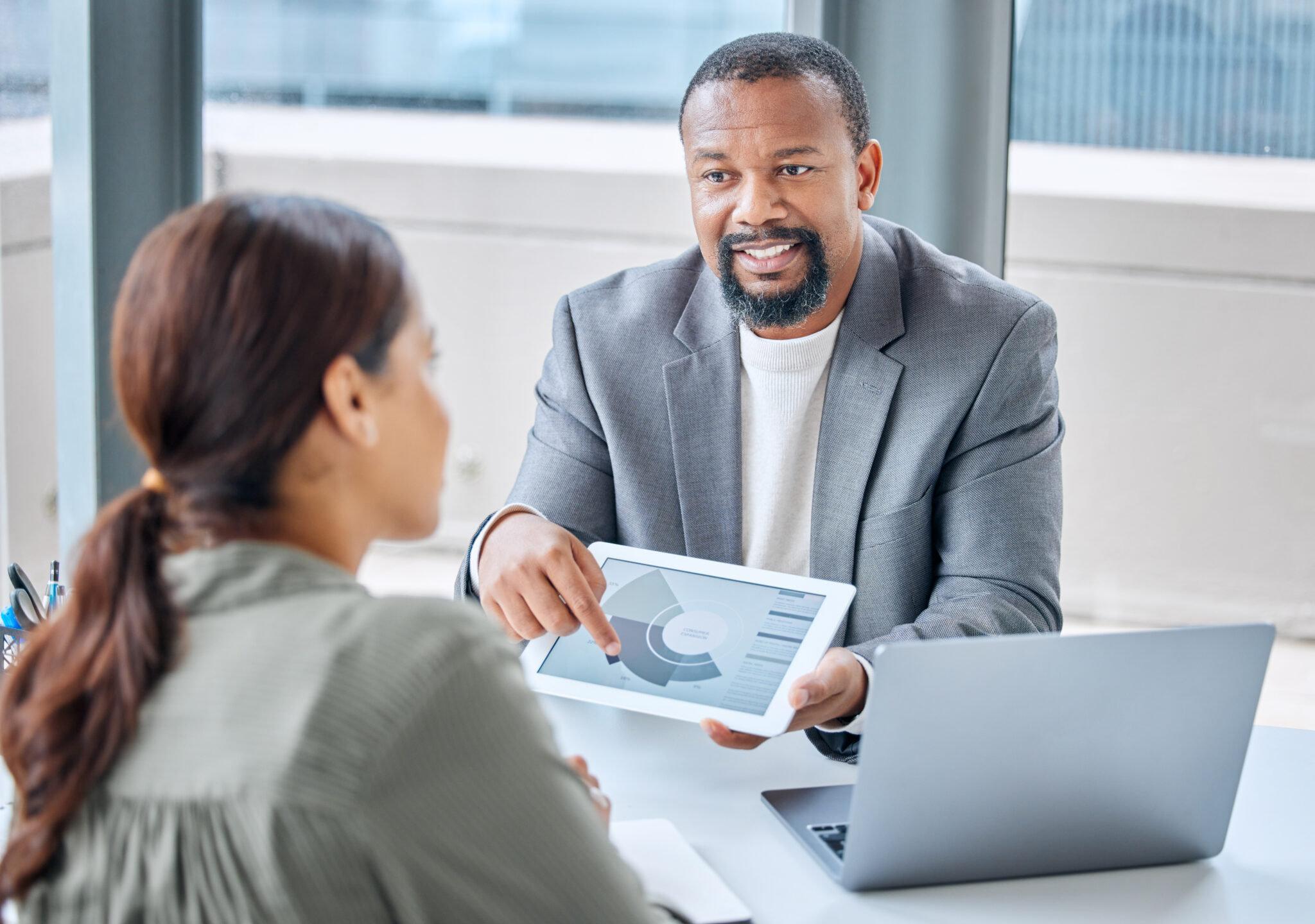 A man and woman seated at a table, engaged with a tablet, representing Excell Digital Marketing Services