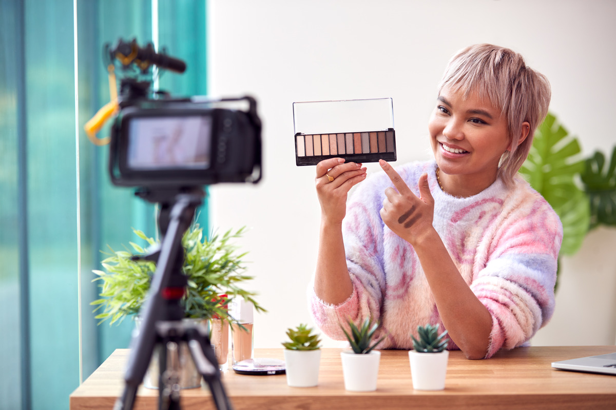 A woman with a camera and makeup kit, embodying 2023 social media marketing trends in content creation and beauty
