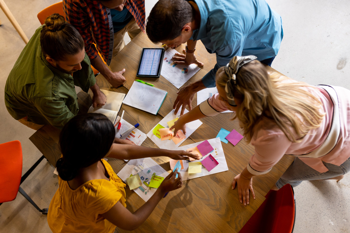 A diverse group of individuals collaborating at a table, analyzing papers related to 2023 social media marketing trends