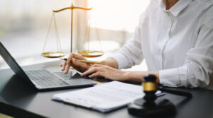 A woman in a white shirt sits at a desk with a laptop and a scale of justice, symbolizing legal content marketing