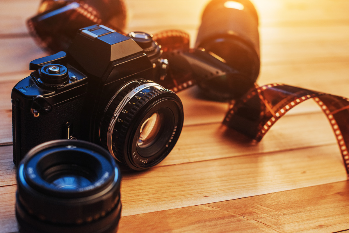 A camera and film reel placed on a table, symbolizing creativity and media production in a Houston social media agency
