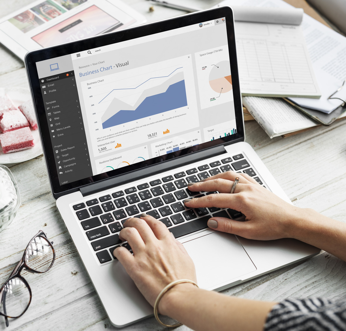 A woman analyzing quarterly SEO reports on a laptop, focusing on a graph displaying performance metrics