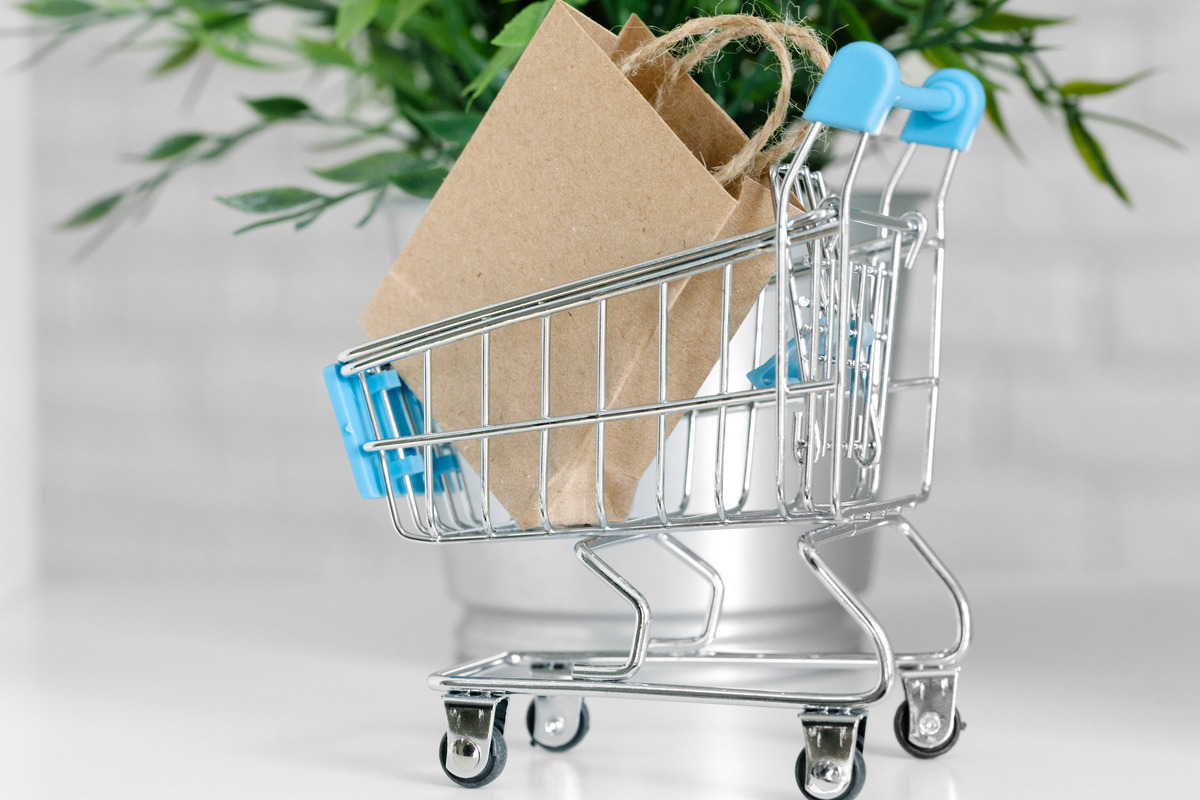 A shopping cart with a paper bag rests on a table, symbolizing convenience in retail shopping experiences