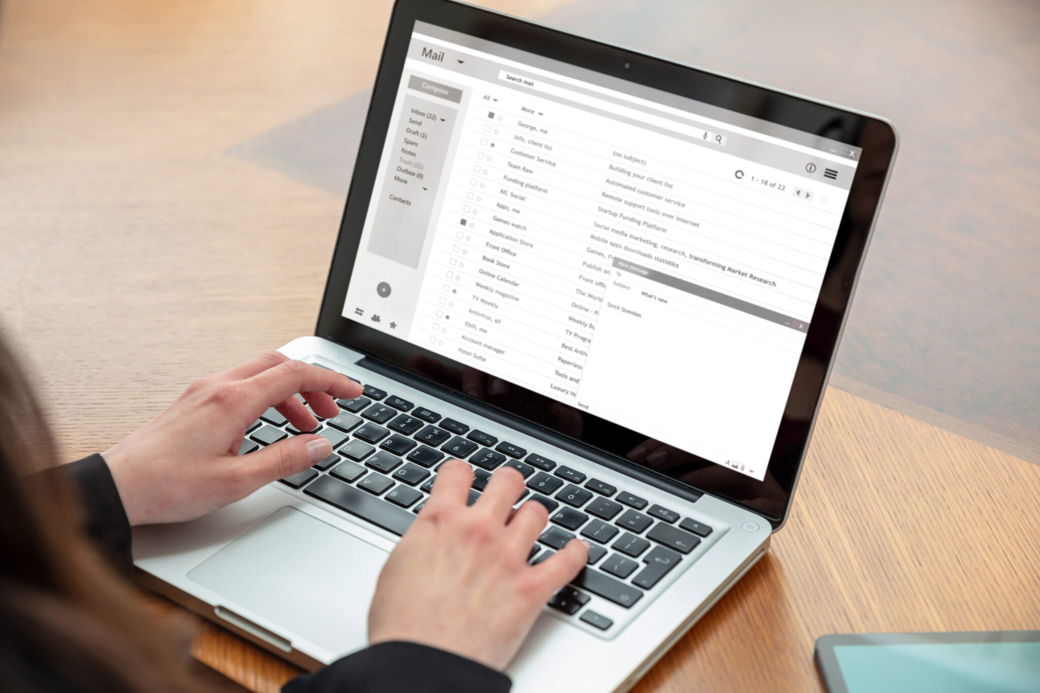 Email marketer typing on a laptop with an open email inbox displaying messages and drafting an email marketing list
