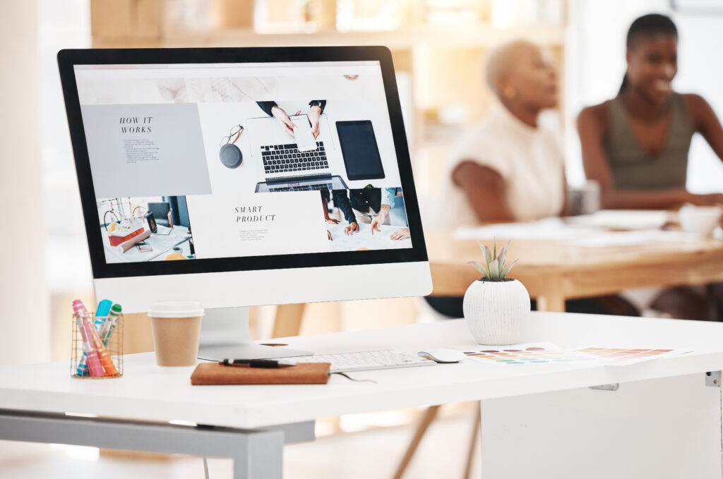A computer monitor displaying a website design with an SEO professional and a client discussing the importance of SEO for lawyers in the background