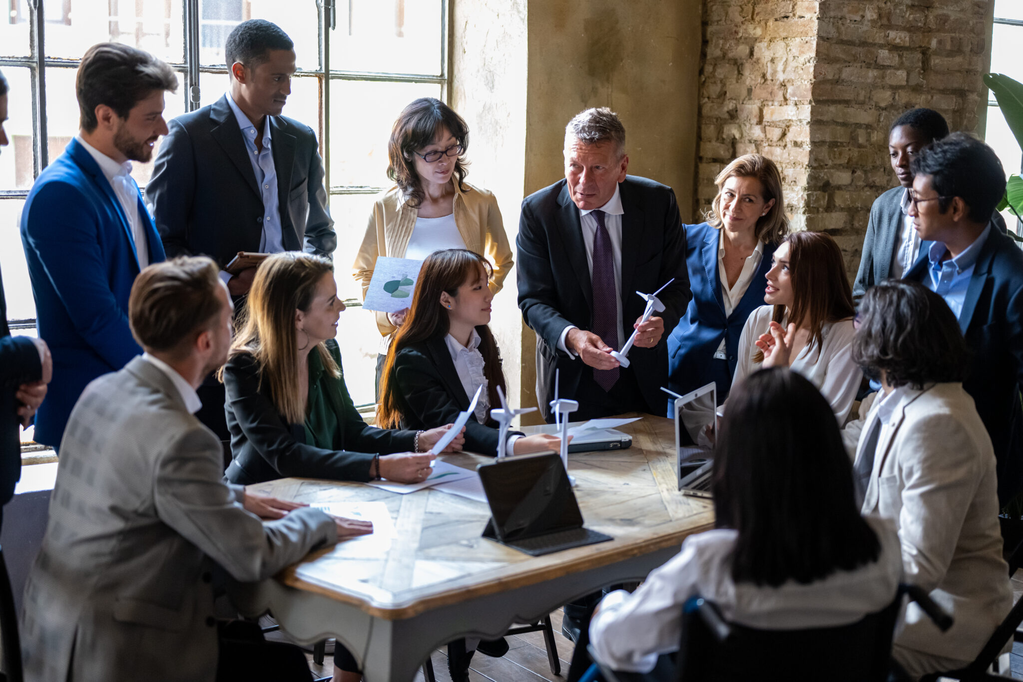 Meeting of senior director with entrepreneurs discussing multiple business projects around a table in a modern office