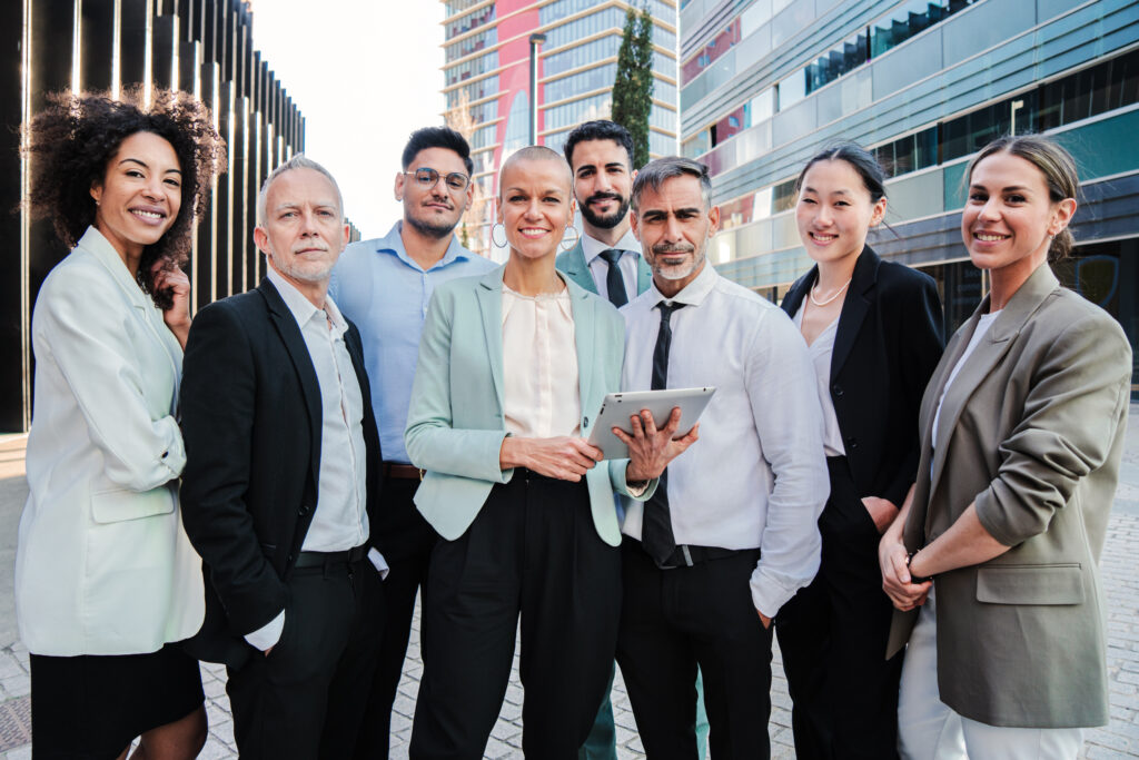 Team of business professionals standing together outdoors, with a cityscape in the background