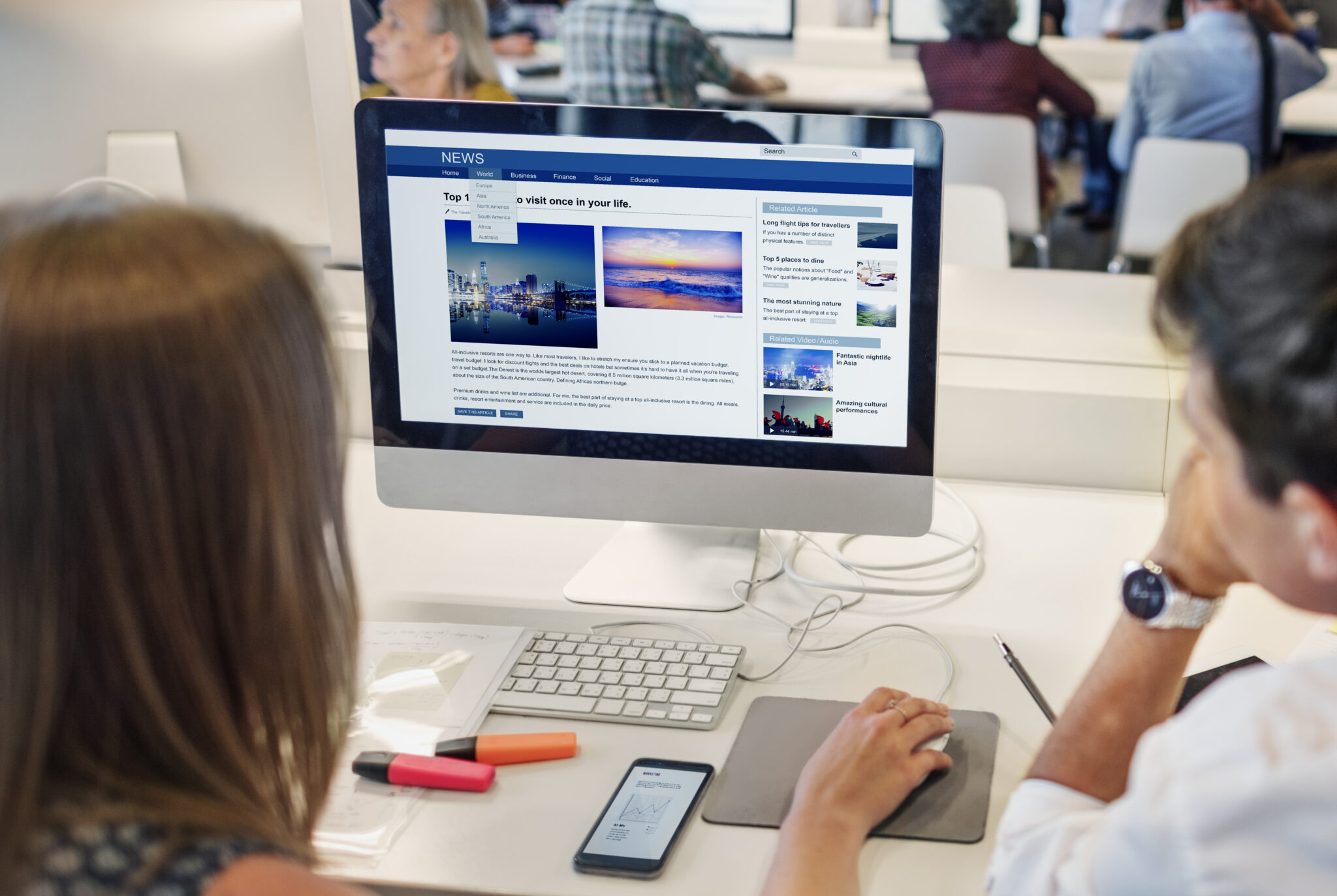 Two email marketers reading a website article on a desktop, sourcing some helpful content to use in their Email Marketing in a modern office