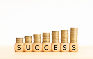 Stack of gold coins spelling out 'SUCCESS' representing entrepreneurs who started from zero