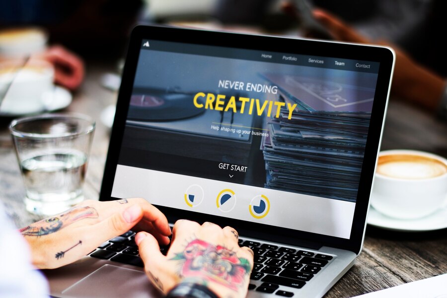 Person working on a laptop displaying a creative website design, emphasizing the importance of an attractive web layout