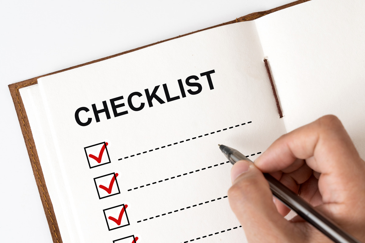 Hand checking off completed items on a business checklist or to-do list