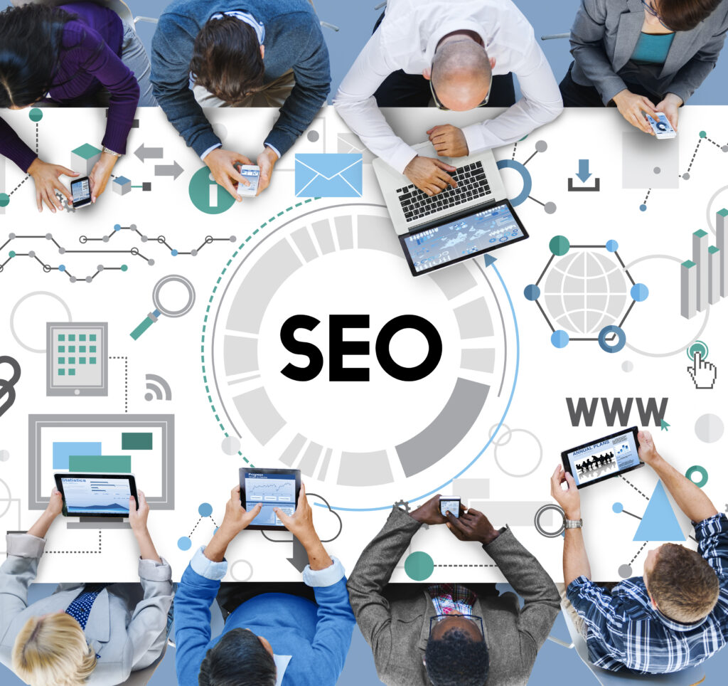 People working at a table with a graphic overlay showing 'SEO' in the center and digital marketing icons