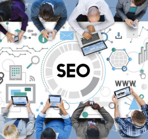 People working at a table with a graphic overlay showing 'SEO' in the center and digital marketing icons