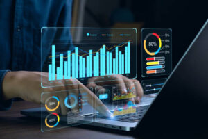 Person working on a laptop, interacting with a futuristic, holographic interface displaying blue bar charts, pie charts, and data analytics dashboards for business strategy