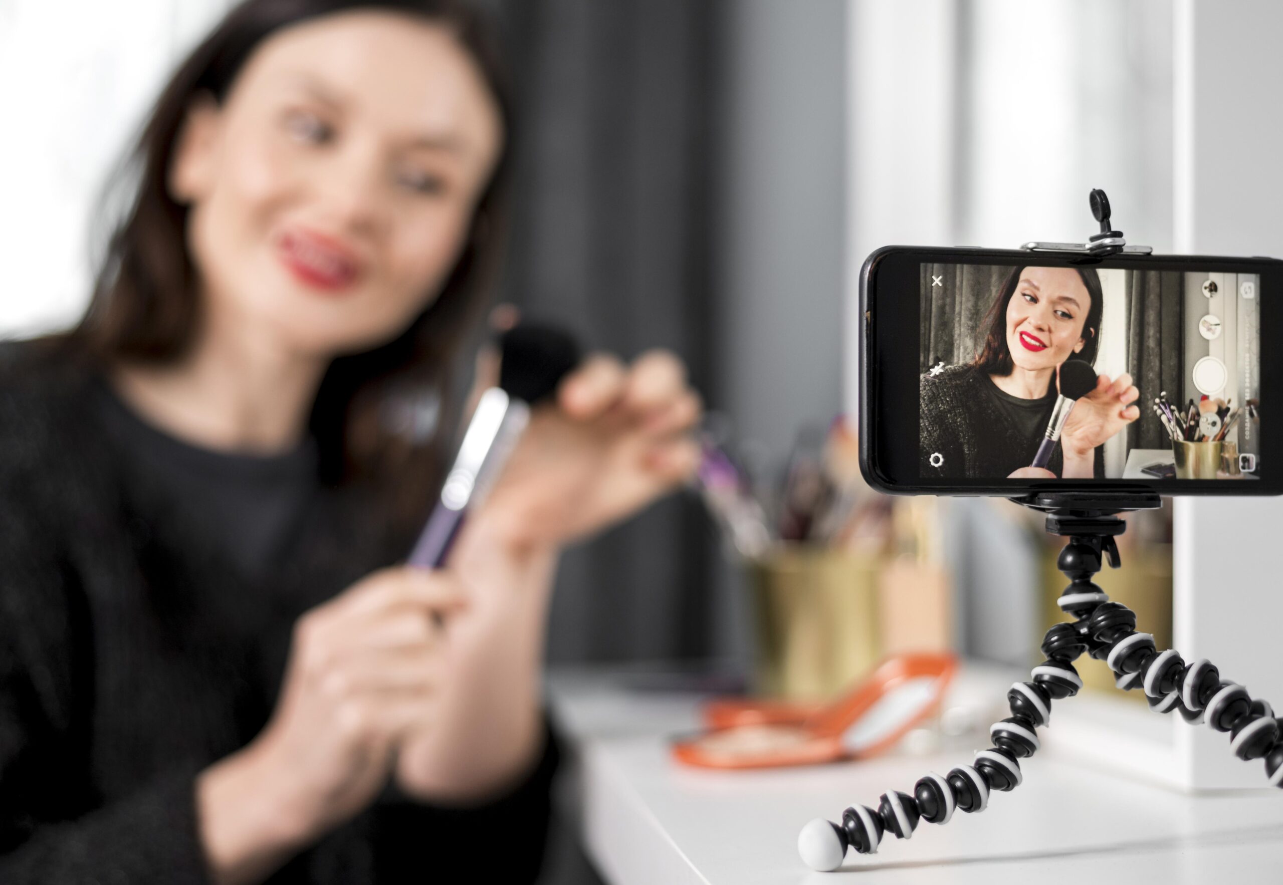 Beauty vlogger recording a makeup tutorial for social media, representing influencer marketing, digital content creation, and mobile video production