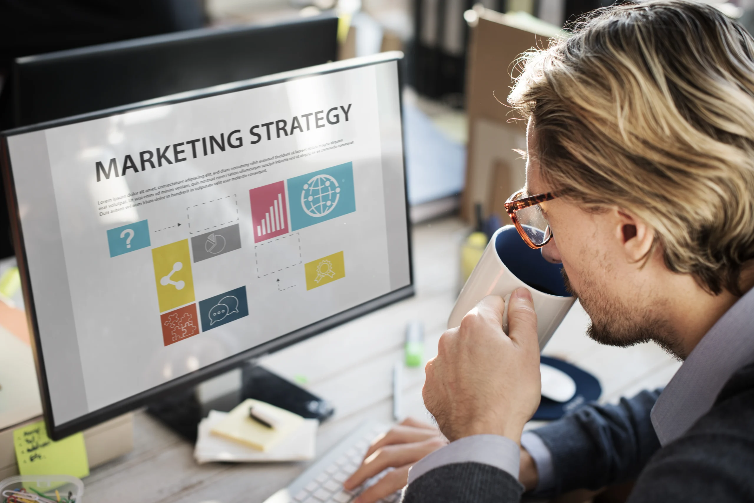 Professional reviewing marketing strategy on computer while drinking coffee, representing business planning, digital marketing analysis, and strategic decision-making