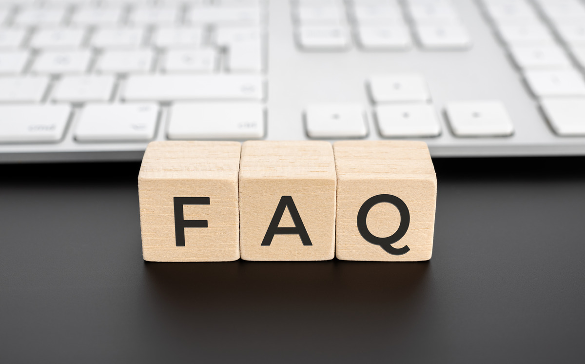 FAQ wooden letter blocks on desk in front of computer keyboard, representing frequently asked questions, customer support resources, help center content, knowledge base articles, and user assistance information.