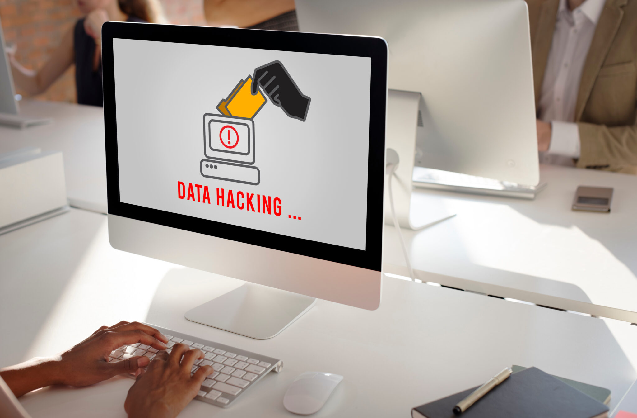 Computer displaying a data hacking warning in an office environment, representing cybersecurity threats, data breaches, ransomware attacks, information security, and protecting sensitive business and customer data