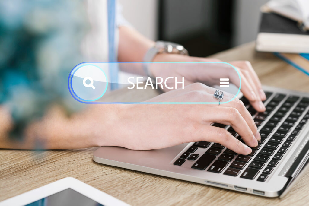 Person typing on a laptop with a digital search bar overlay, representing online search, search engine optimization (SEO), keyword research, search intent, and improving website visibility in search results.