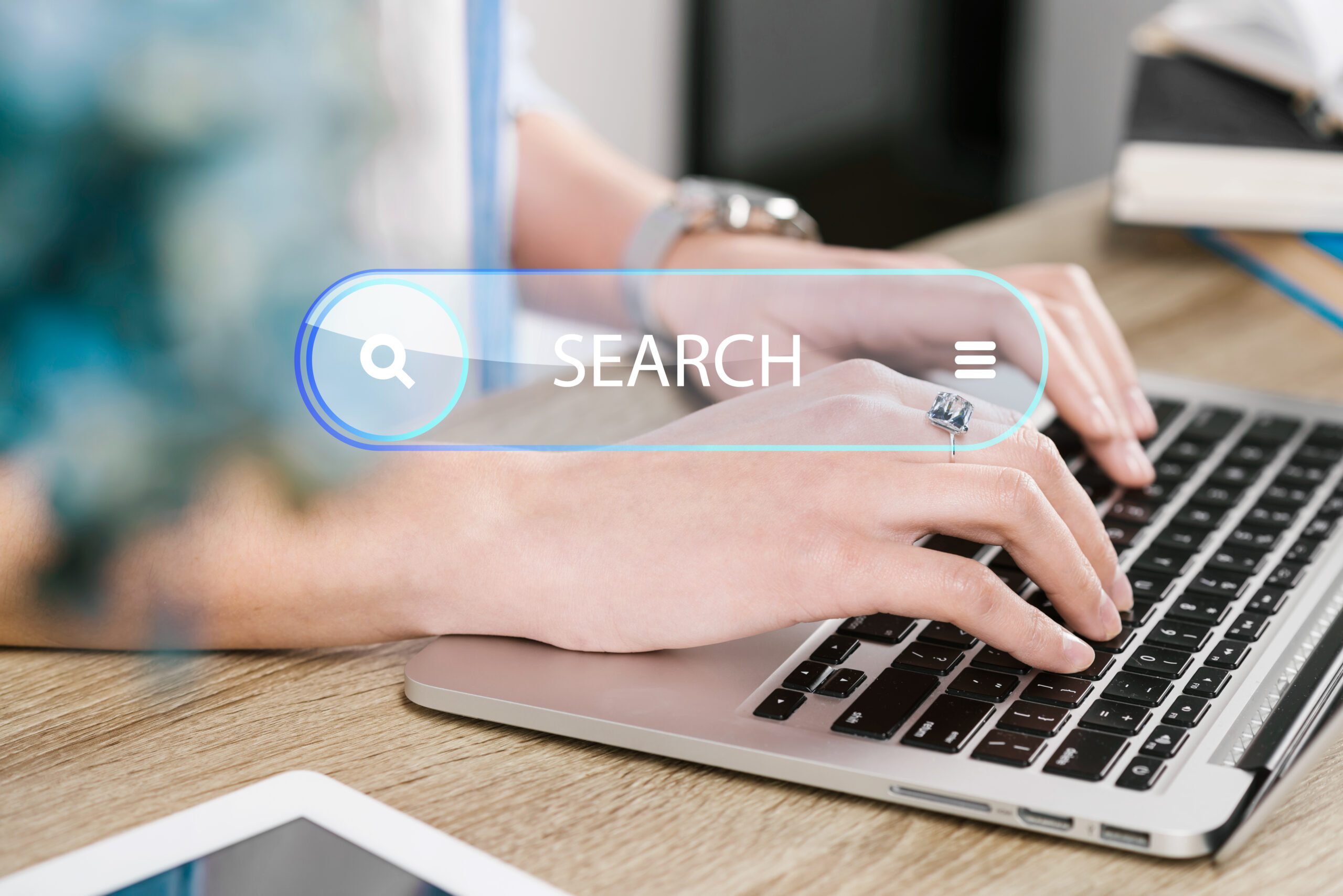 Person typing on a laptop with a digital search bar overlay, representing online search, search engine optimization (SEO), keyword research, search intent, and improving website visibility in search results.
