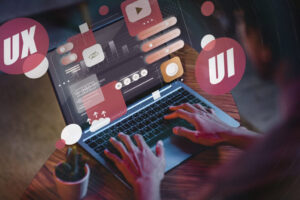 Web designer working on a laptop with UI and UX interface elements, representing website design, user experience, responsive web development, conversion optimization, and digital marketing services.